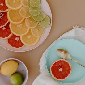 plates with sliced citrus fruits with cutlery near bowl